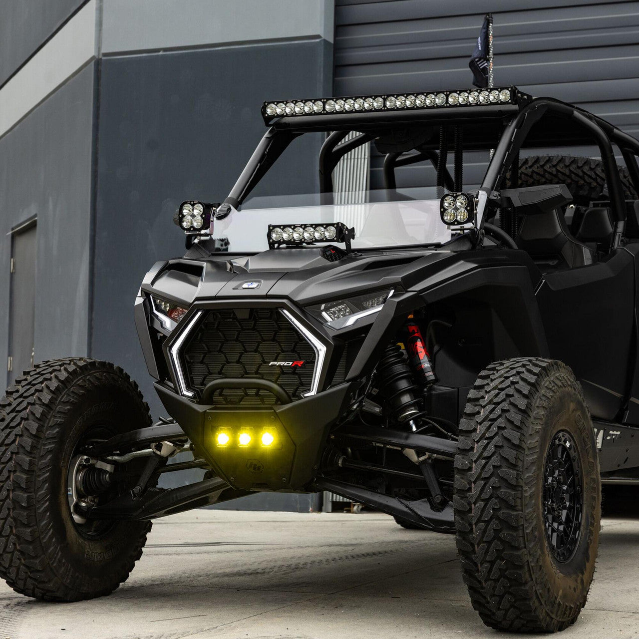 Black off-road vehicle with additional lights in front of a gray building