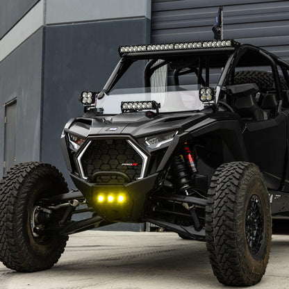 Black off-road vehicle with additional lights in front of a gray building